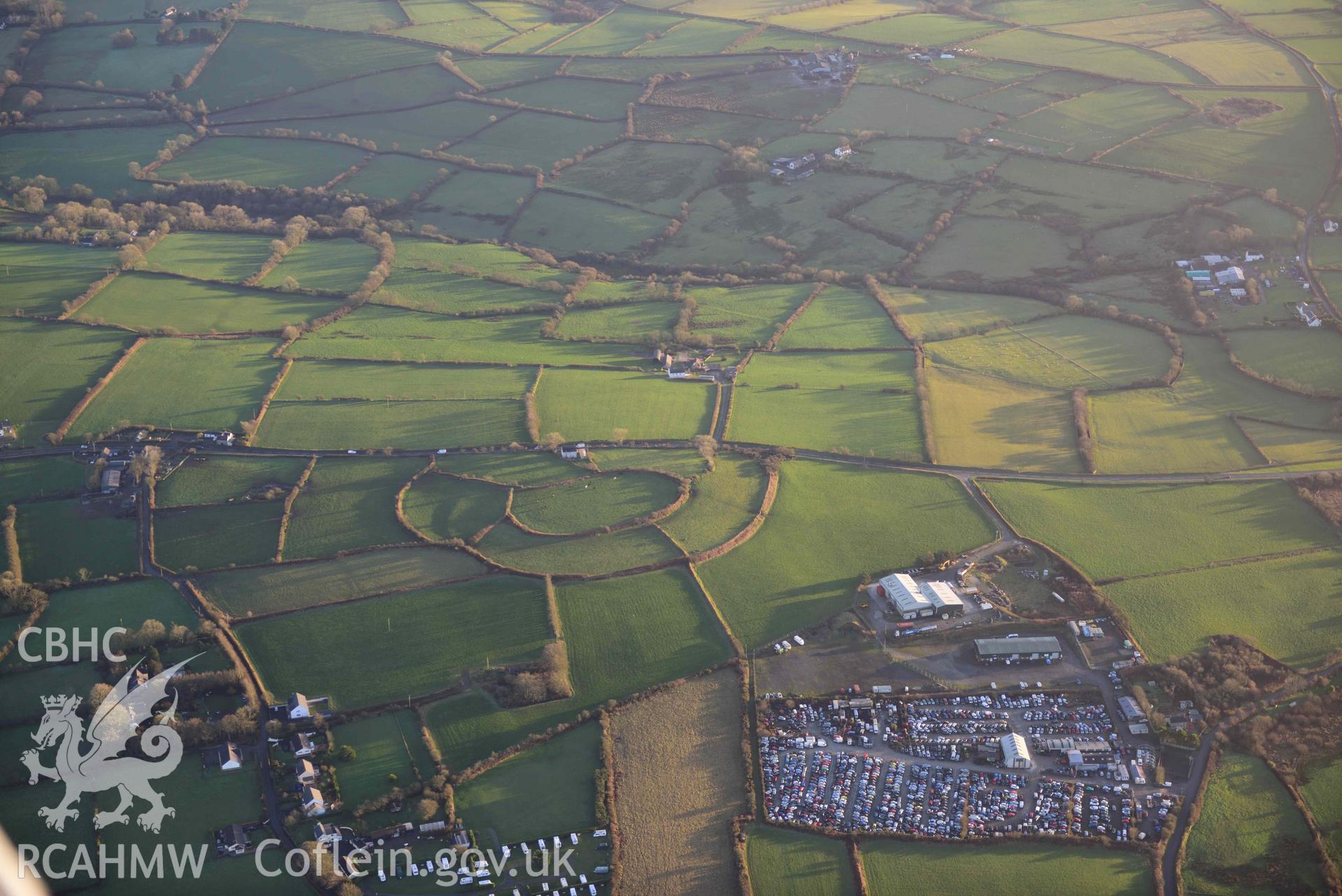 Oblique aerial photograph of Castell Nadolig hillfort, view from north west in low winter light. Taken during the Royal Commission