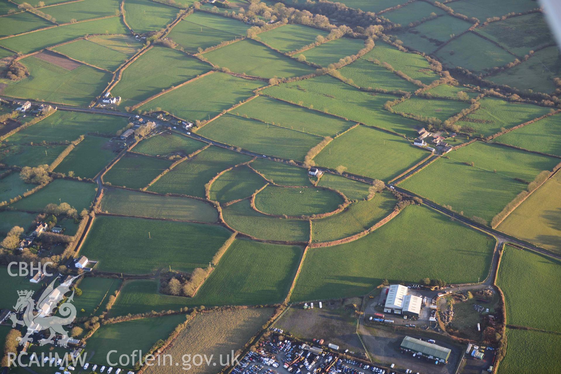 Oblique aerial photograph of Castell Nadolig hillfort, view from north west in low winter light. Taken during the Royal Commission