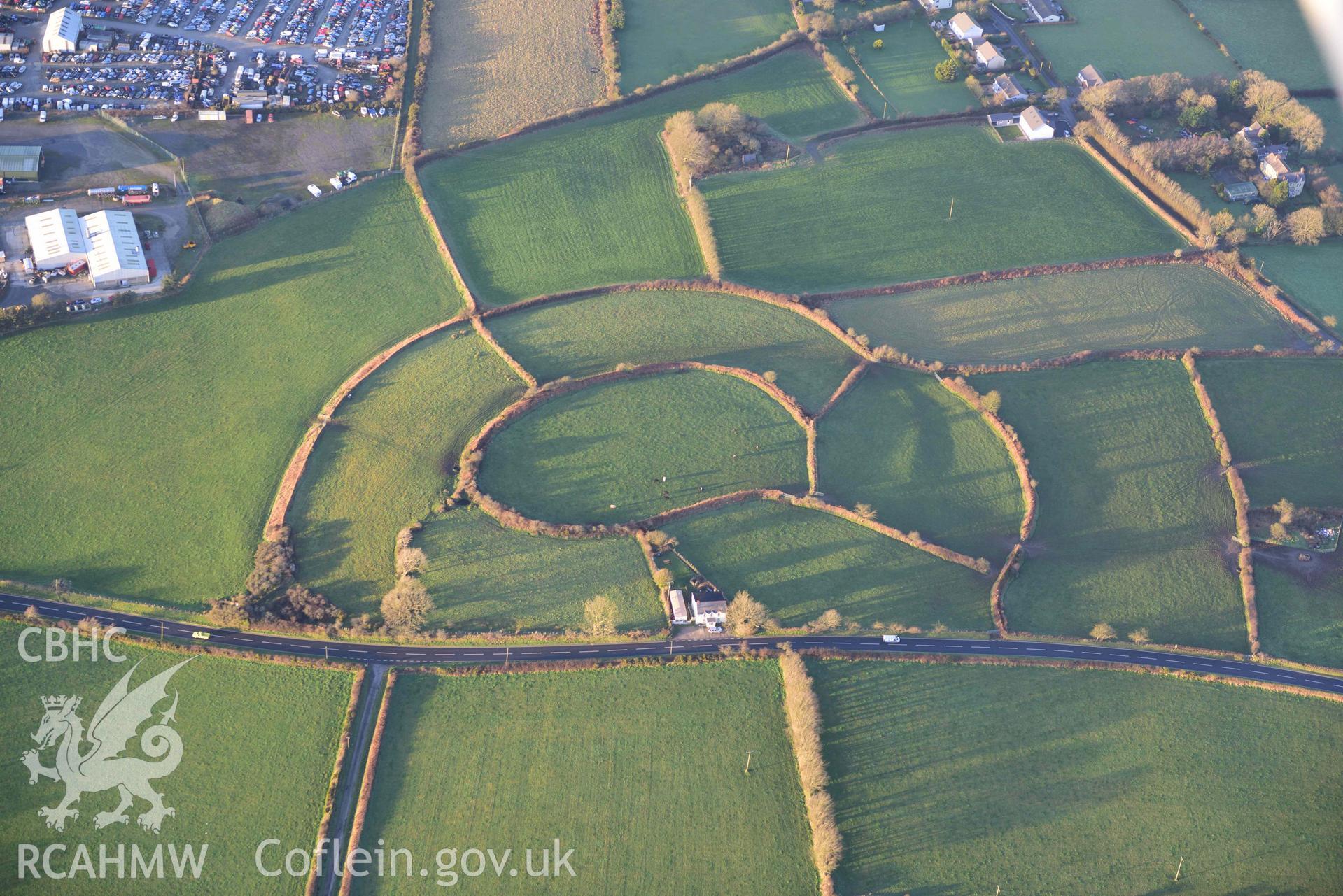 Oblique aerial photograph of Castell Nadolig hillfort, view from south in low winter light. Taken during the Royal Commission