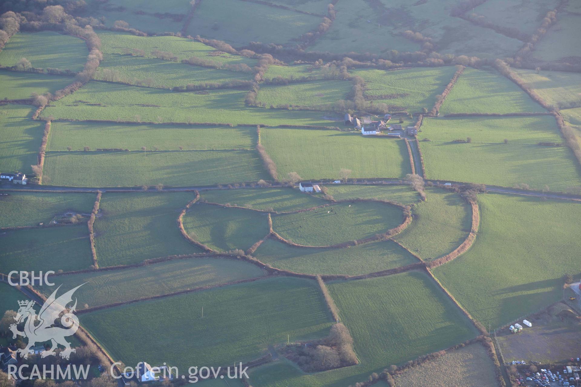 Oblique aerial photograph of Castell Nadolig hillfort, view from north in low winter light. Taken during the Royal Commission