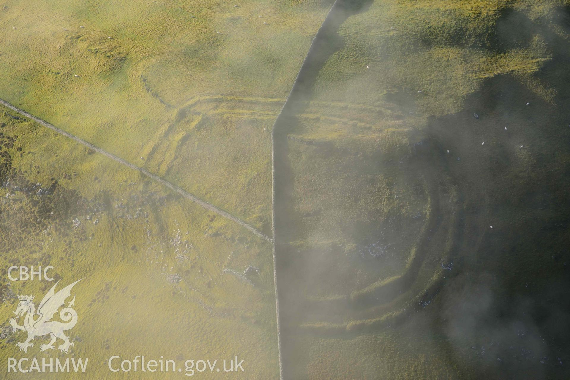 Oblique aerial photograph of Moel Goedog hillfort, with drifting cloud, taken during the Royal Commission