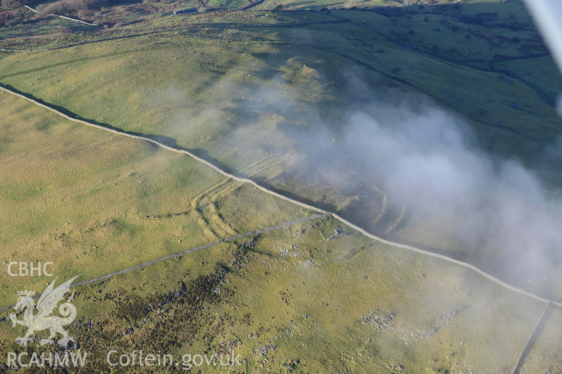 Oblique aerial photograph of Moel Goedog hillfort, with drifting cloud, taken during the Royal Commission