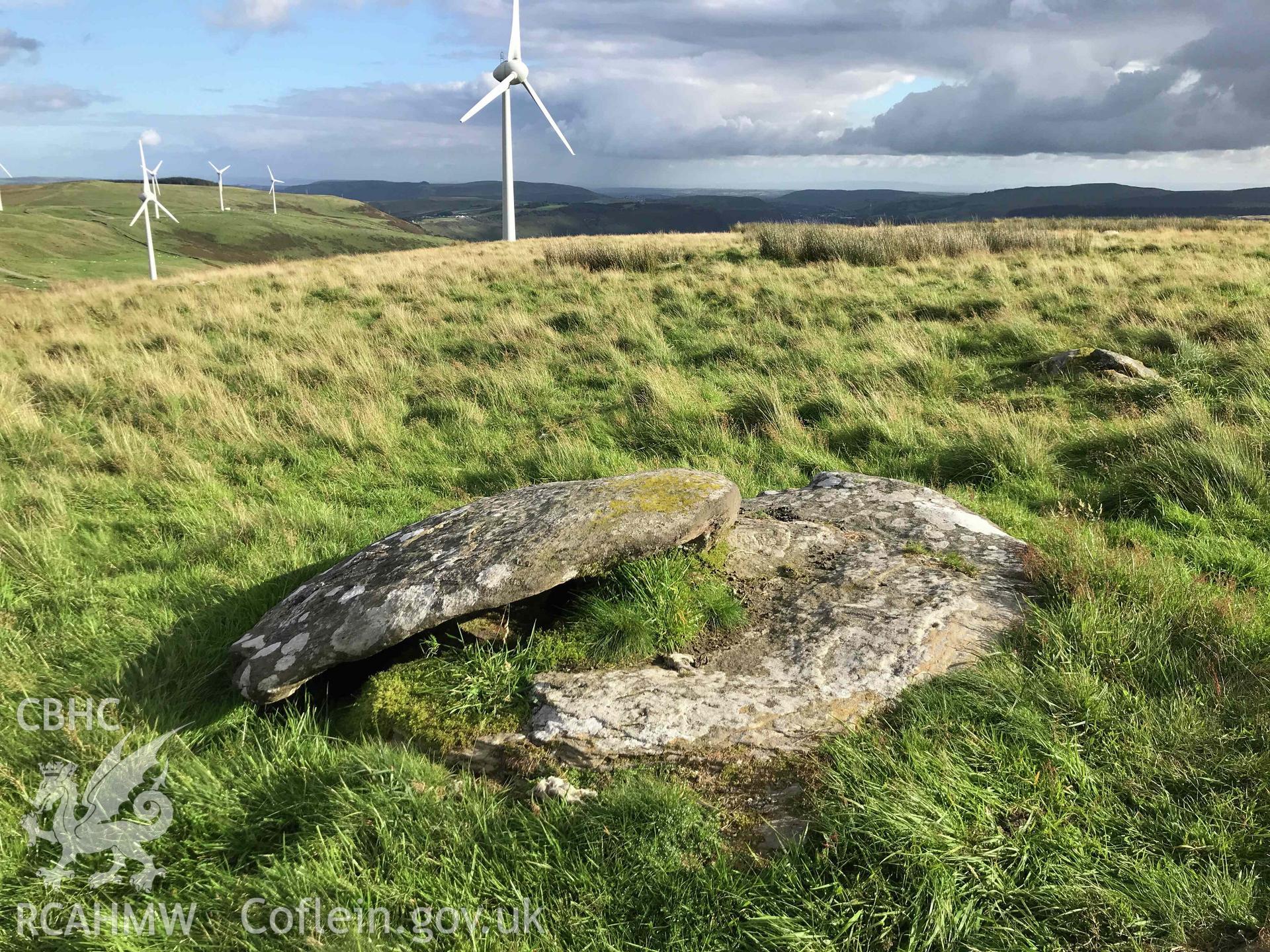 Digital photograph of logen stone near Tarren Maerdy cairn with windmills in background, produced by Paul Davis in 2020