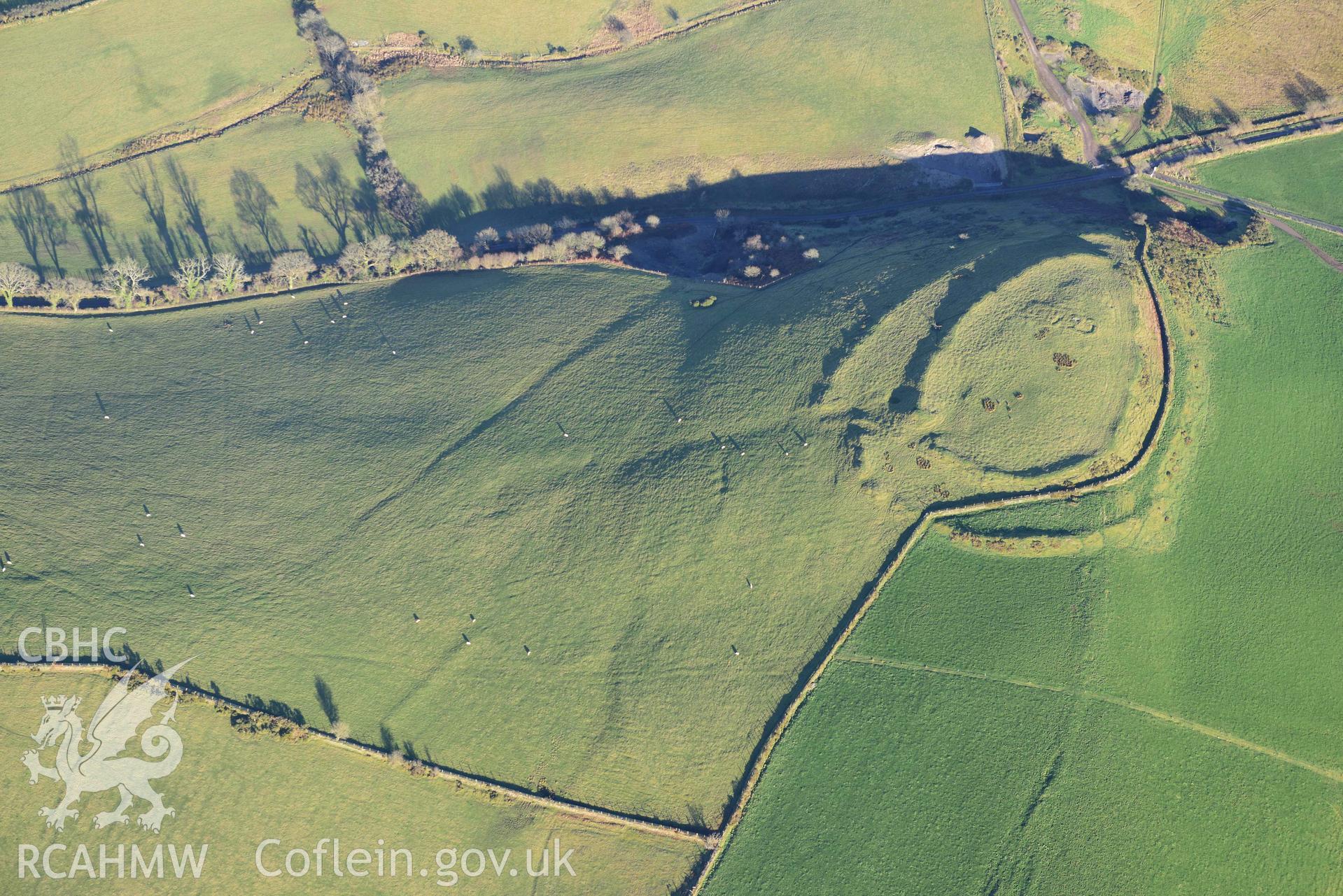 Oblique aerial photograph of Castell Perthi Mawr, with earthworks of prehistoric fields to the north west. Taken during the Royal Commission’s programme of archaeological aerial reconnaissance by Toby Driver on 17th January 2022