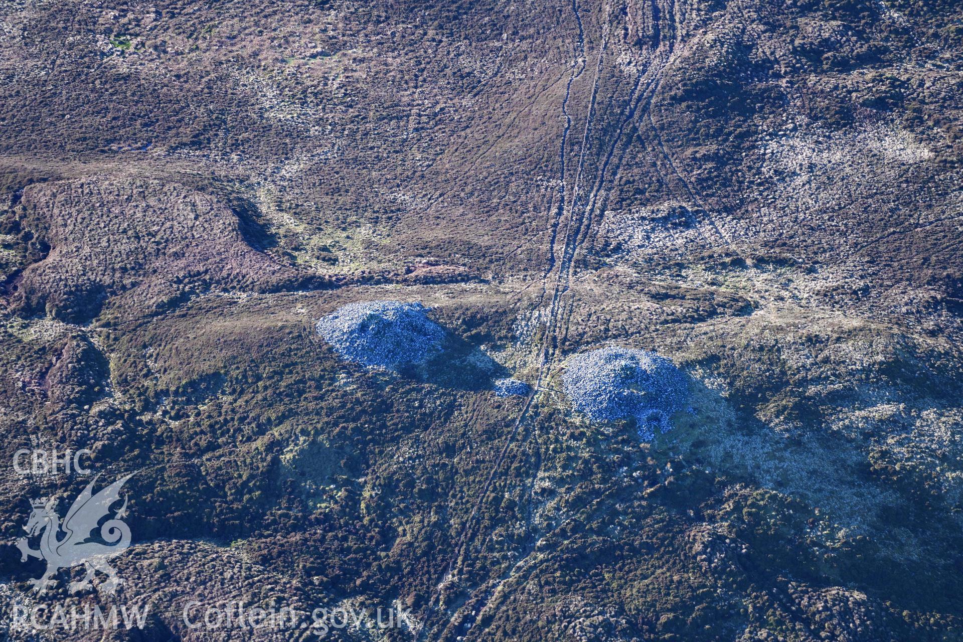 Oblique aerial photograph of cairn pair and outlier at Cairn Biga cairn taken during the Royal Commission’s programme of archaeological aerial reconnaissance by Toby Driver on 17th January 2022