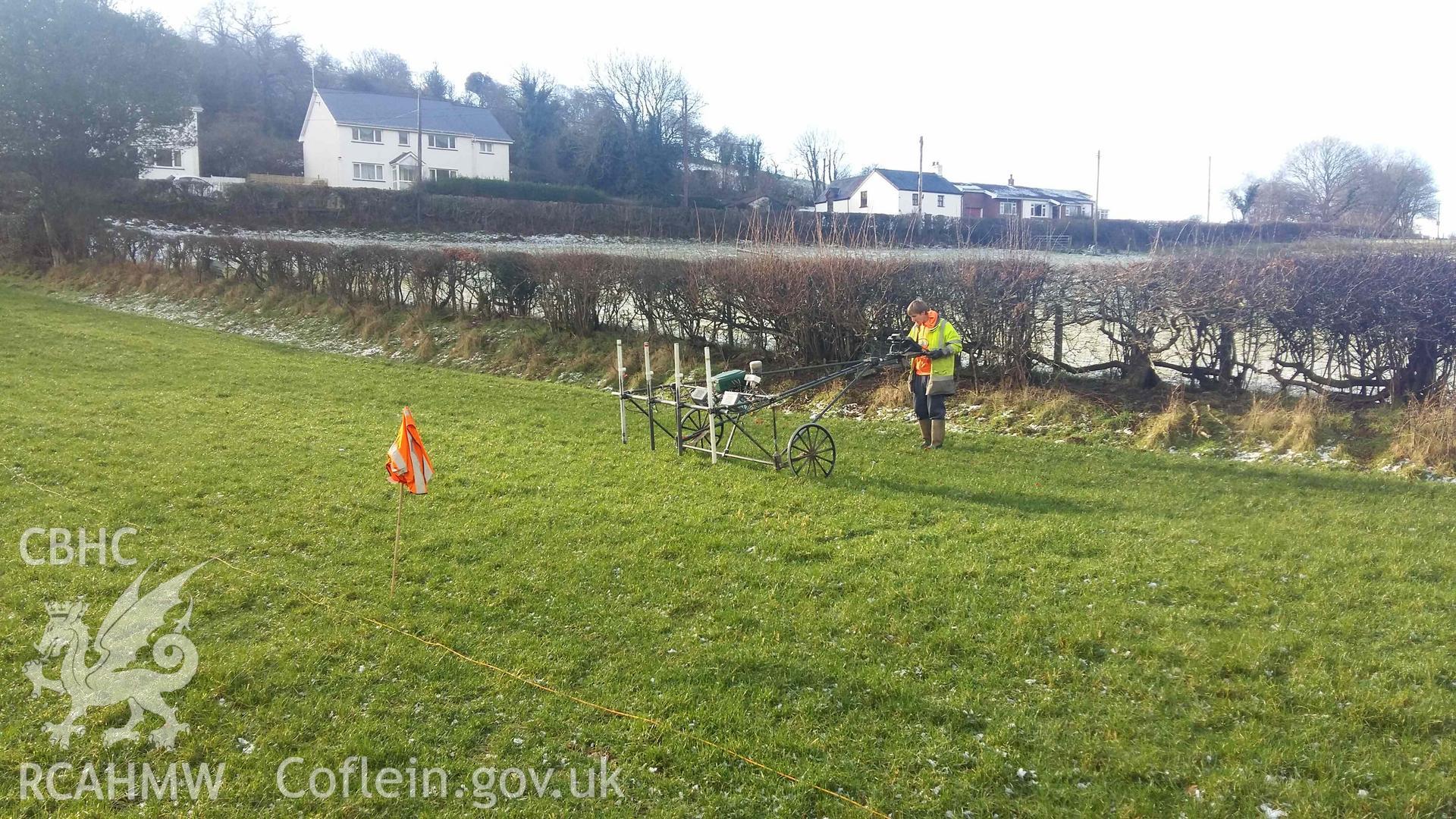 Photograph looking south west showing SUMO geophysics survey staff with cart at south-west edge of field, taken by Sumo Survey on 25 January 2021. Part of Geophysical Survey of Pen y Wal, Dollwen Barrow, Goginan. Commissioned by the RCAHMW and produced by Sumo Survey, 2021.