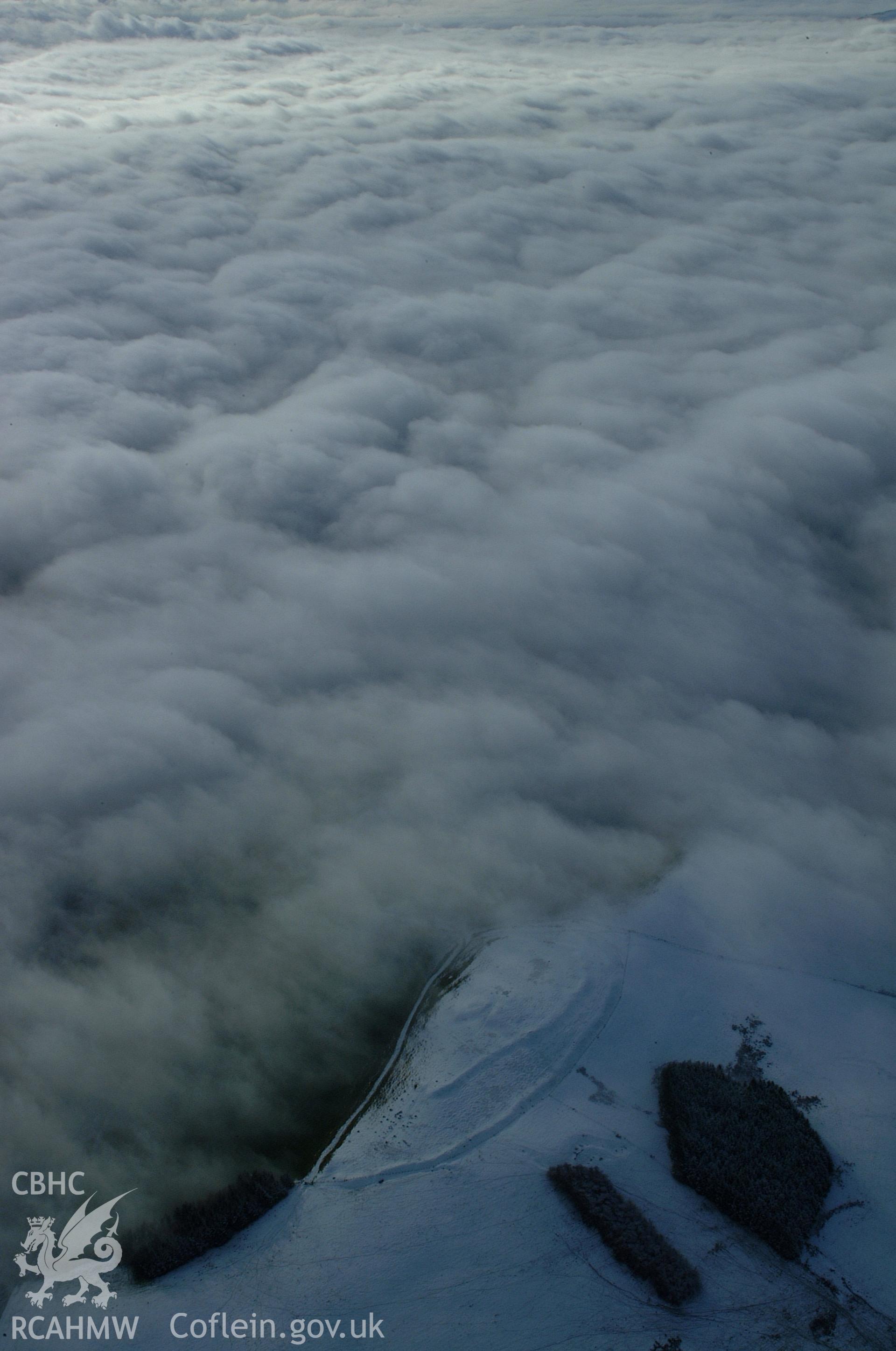 RCAHMW colour oblique aerial photograph of Y Gaer from the north-east. A stunning high winter view showing the site under snow on the on edge of freezing fog. Taken on 19 November 2004 by Toby Driver