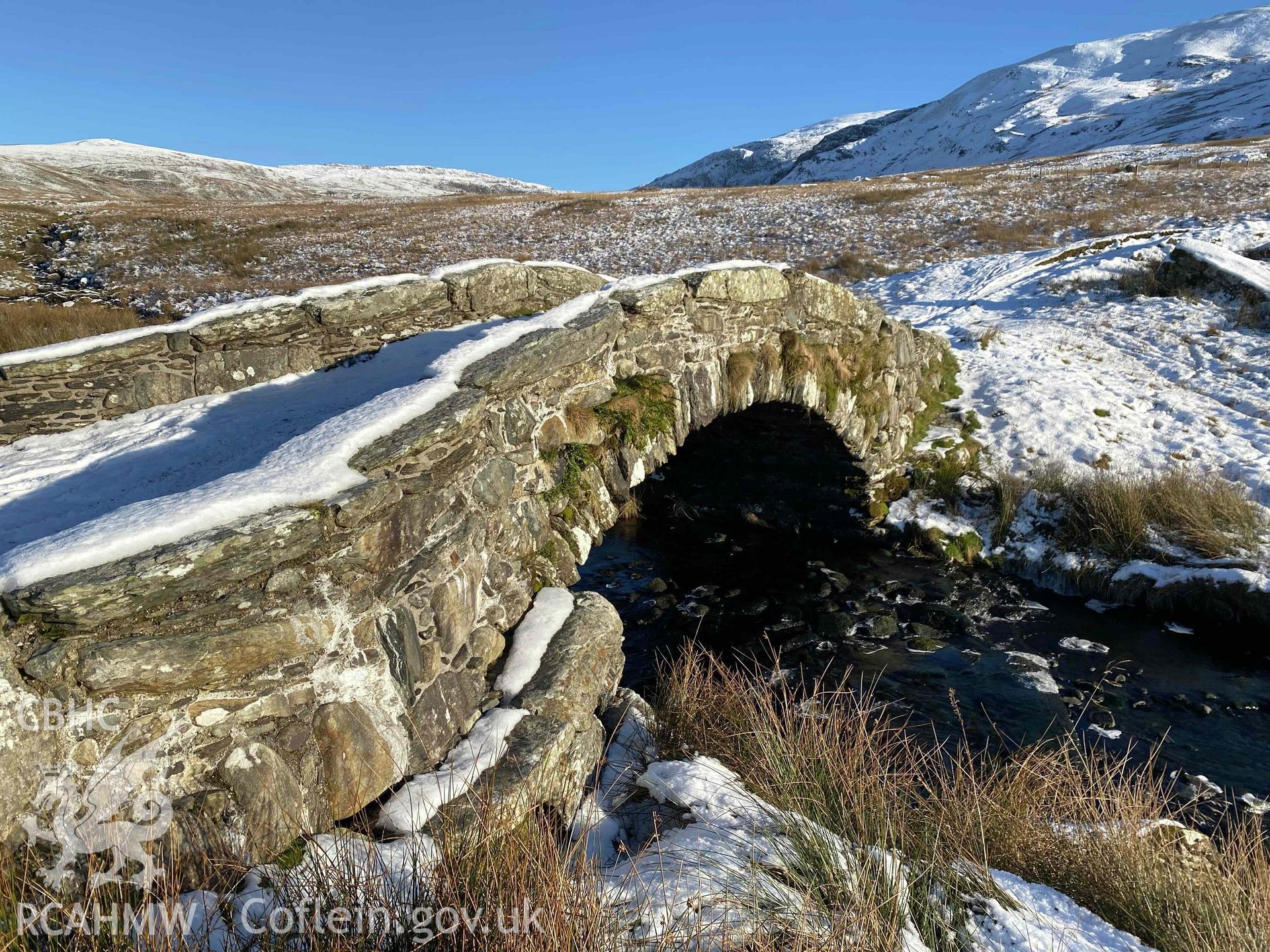 Digital photograph of Pont Scethin Packhorse Bridge in snow, produced by Paul Davis in 2023