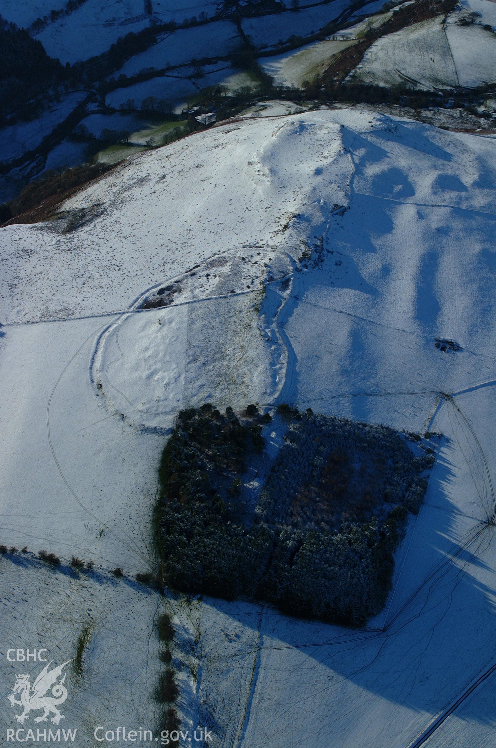 RCAHMW colour oblique aerial photograph of Cerrig Gwynion Defended Enclosure. A view from the east with the monument under snow. Taken on 19 November 2004 by Toby Driver