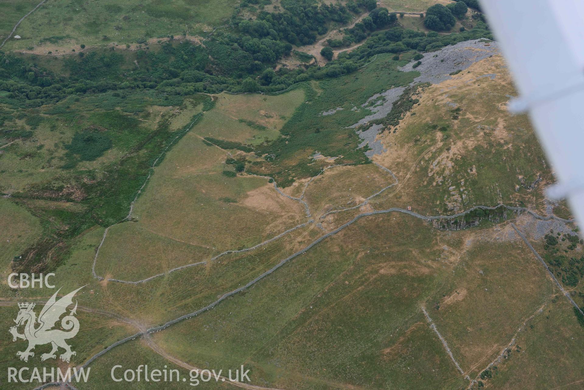 Dinas Llanfairfechan and hut circles near Dinas. Oblique aerial photograph taken during the Royal Commission’s programme of archaeological aerial reconnaissance by Toby Driver on 10 July 2018.