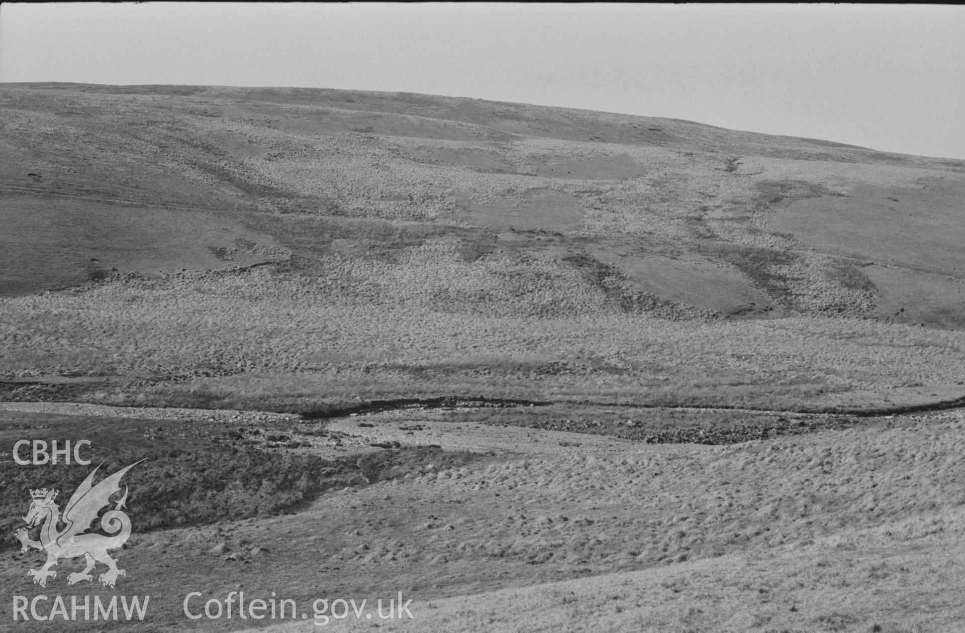 Digital copy of a black and white negative showing view across the Afon Claerwen to Esgair Hengae, showing old road sloping down from left to right, ruins of Hengae (just right of centre) and Rhyd Hengae (extreme right). Panoramic view, photo 2 of 3. Photographed by Arthur Chater on 8 April 1969. Grid Reference SN 8220 6780.