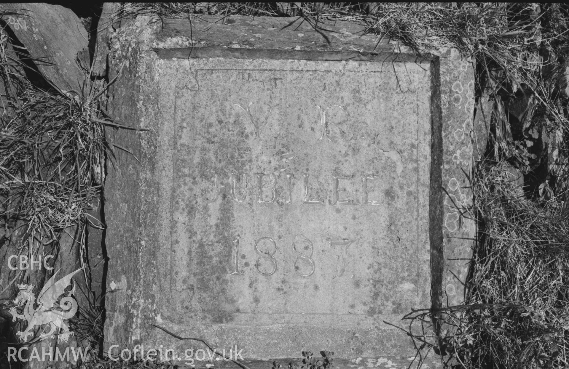 Digital copy of a black and white negative showing slate inscribed V R / JUBILEE / 1887 on bank/wall on the east side of the main road 120m up from the bridge at Llechryd. Photographed by Arthur Chater on 7 April 1969. Looking East from Grid Reference SN 2174 4378.