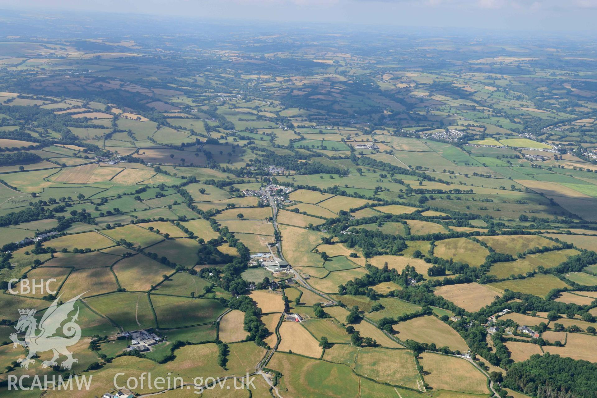 Castell Trefilan and distant view of Talsarn village from the north east. Oblique aerial photograph taken during the Royal Commission’s programme of archaeological aerial reconnaissance by Toby Driver on 10 July 2018.