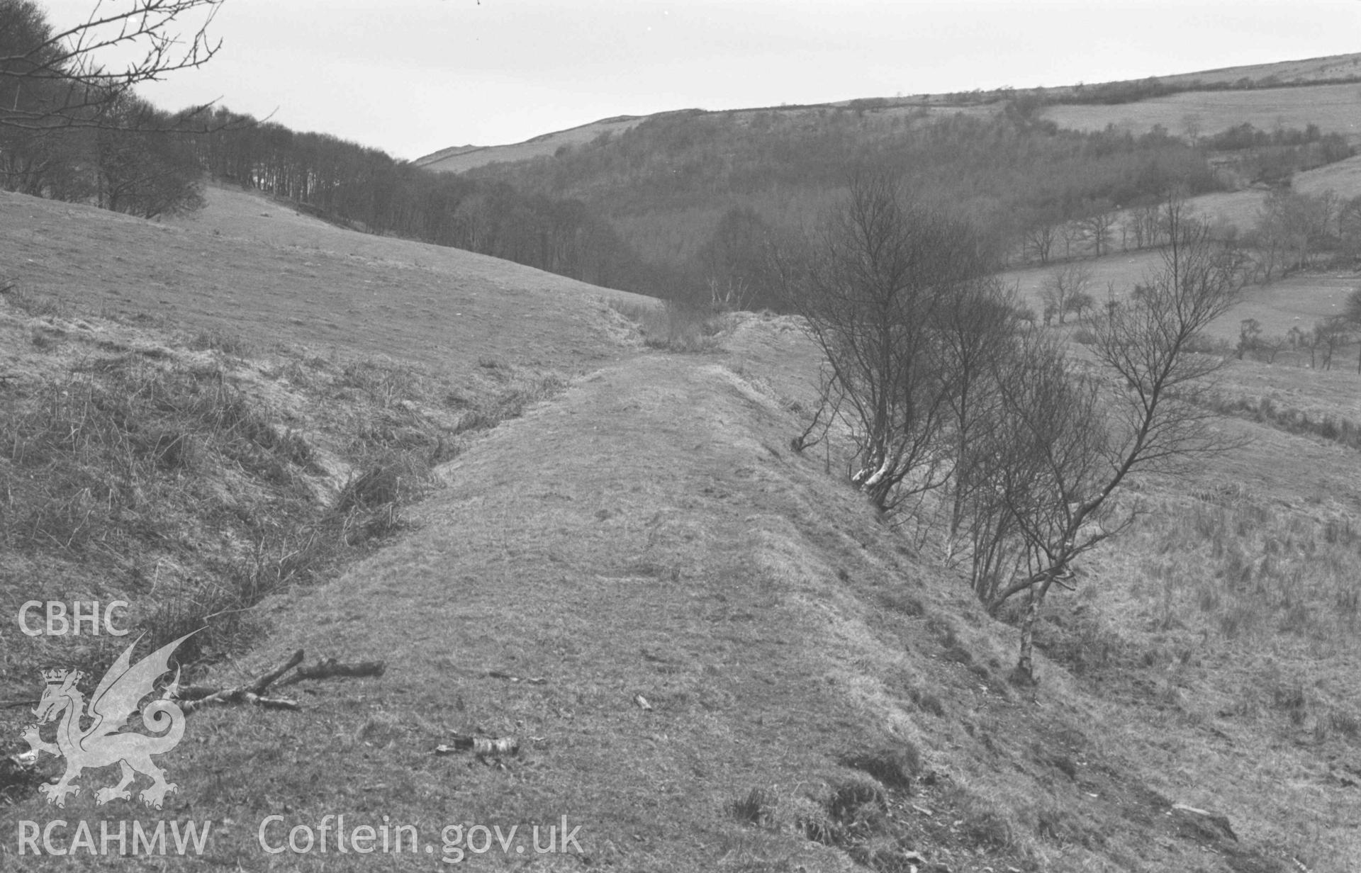 Digital copy of a black and white negative showing track of Hafan-Llandre railway, from where it is crossed by the road to Capel Bethesda. Photographed by Arthur Chater on 13 April 1969. Looking west north west from Grid Reference SN 6914 8850.