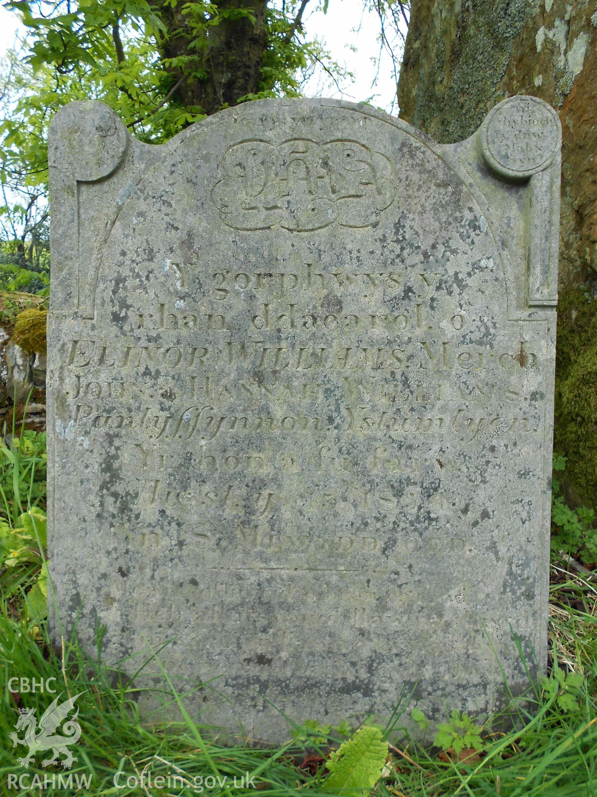 Digital photograph showing grave in memory of Elinor Williams in area B at St John's church, Ysbyty Cynfyn (B29).

Inscription B29: Yn canus yn yr awr/ YMA/ Y gorphwys y/ rhan ddaearol. o/ ELINOR WILLIAMS. Merch/ JOHN a HANNAH WILLIAMS./ Pantyfynnon. Ystumtyen./ Yr hon a fu farw./ Awst y 13 1854./ Yn 8 MLWYDD OED./ Mewn coffin cul o bren cai fod/ Heb allu symud llaw na thraid/ Am corff yn llawn o bryfed byw/ Am henaid bach i gyda Duw/ Sef. yr Hymn a arferai ganu tra yn y byd.

Description: In the top right hand corner in a circle is the inscription ni thybioch y daw mab y dyn.

This grave was photographed as part of a Graveyard Survey carried out with the help of volunteers in 2013.