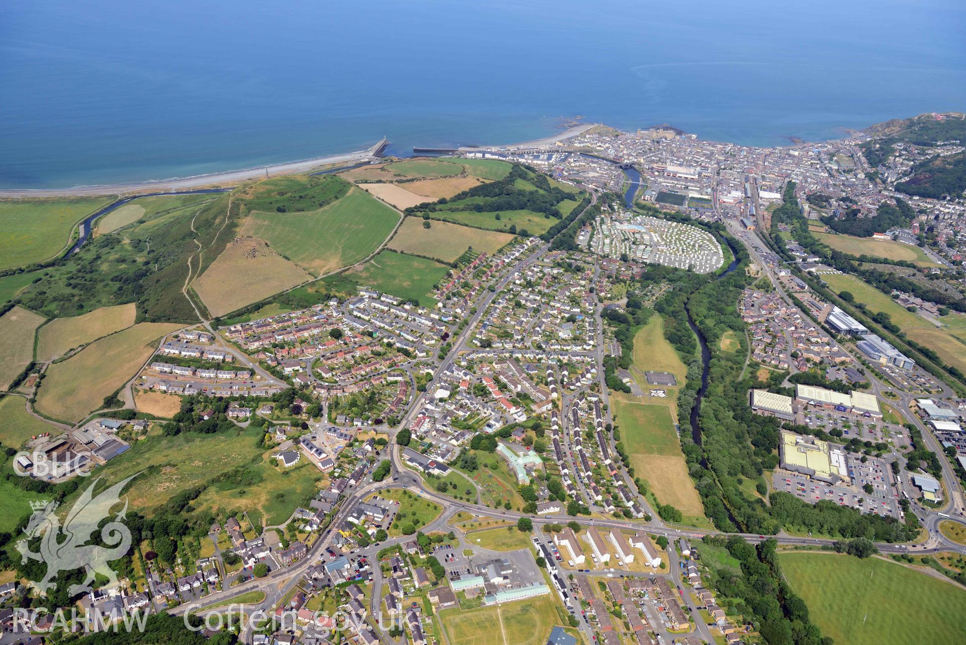 UAV image showing Pendinas with Penparcau and Aberystwyth in the background, taken in June 2023.The image was used as an illustration in the publication 'Discovering Pendinas Hillfort, Penparcau, Aberystwyth'. From a UAV Photographic survey of Pendinas Hillfort, produced by Dr Toby Driver of RCAHMW in 2023.