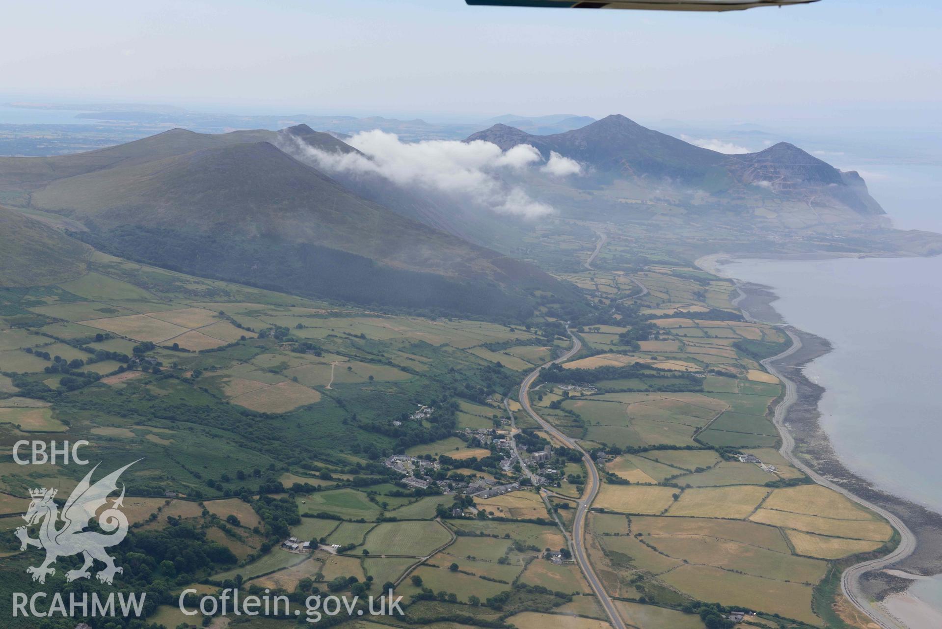 Landscape around Tre'r Ceiri and Clynnog Fawr village. Oblique aerial photograph taken during the Royal Commission’s programme of archaeological aerial reconnaissance by Toby Driver on 10 July 2018.