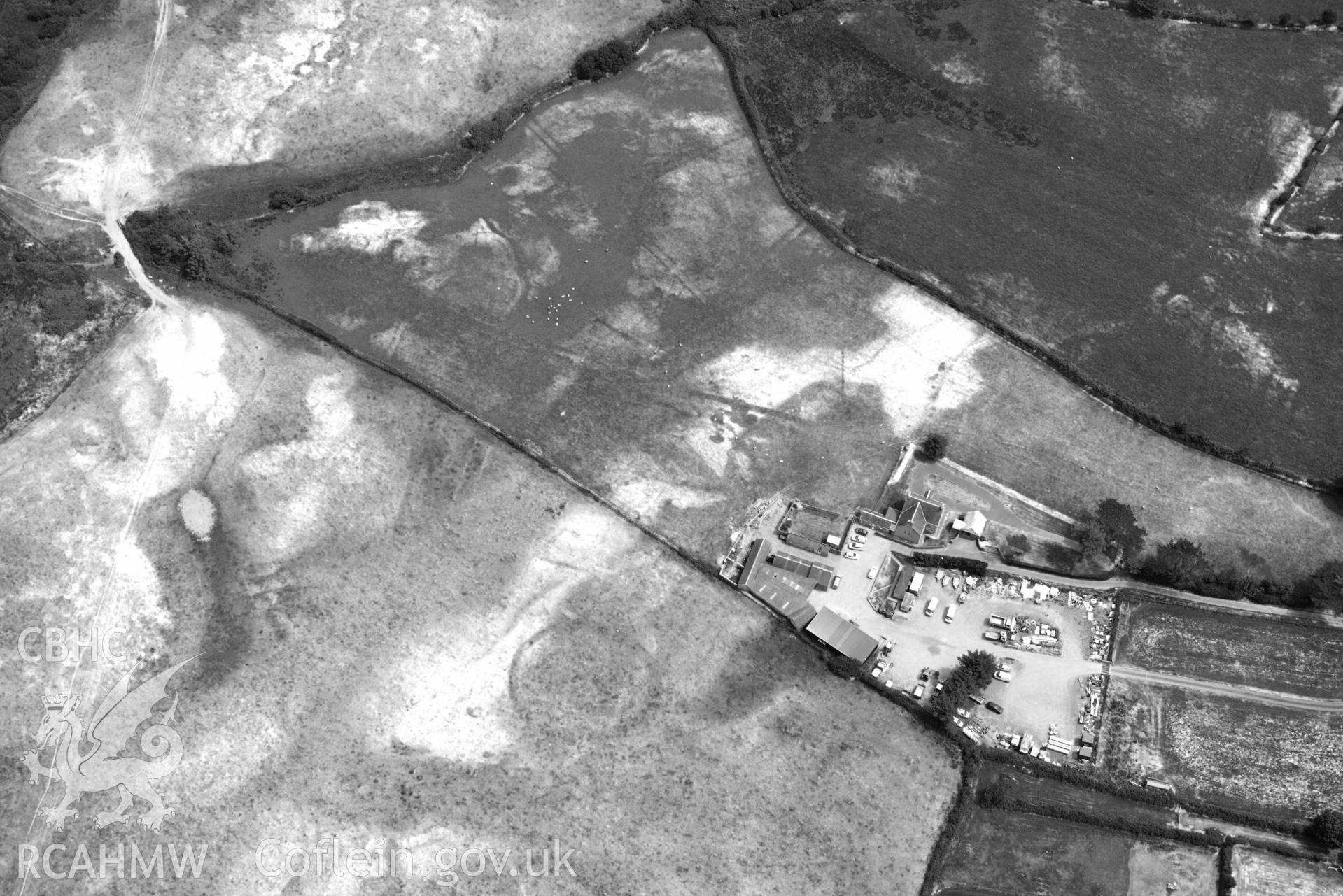 Pwll Parc cropmark enclosure west of Morfa Nefyn. Oblique black and white aerial photograph taken during the Royal Commission’s programme of archaeological aerial reconnaissance by Toby Driver on 10 July 2018.