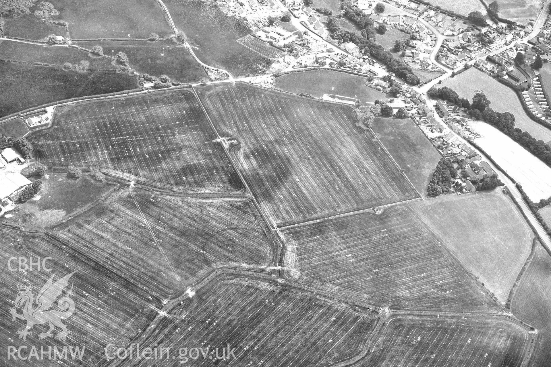 Enclosures to the west of Gwyddelfynydd, part of the Bryncrug cropmarks complex. Oblique black and white aerial photograph taken during the Royal Commission’s programme of archaeological aerial reconnaissance by Toby Driver on 10 July 2018.