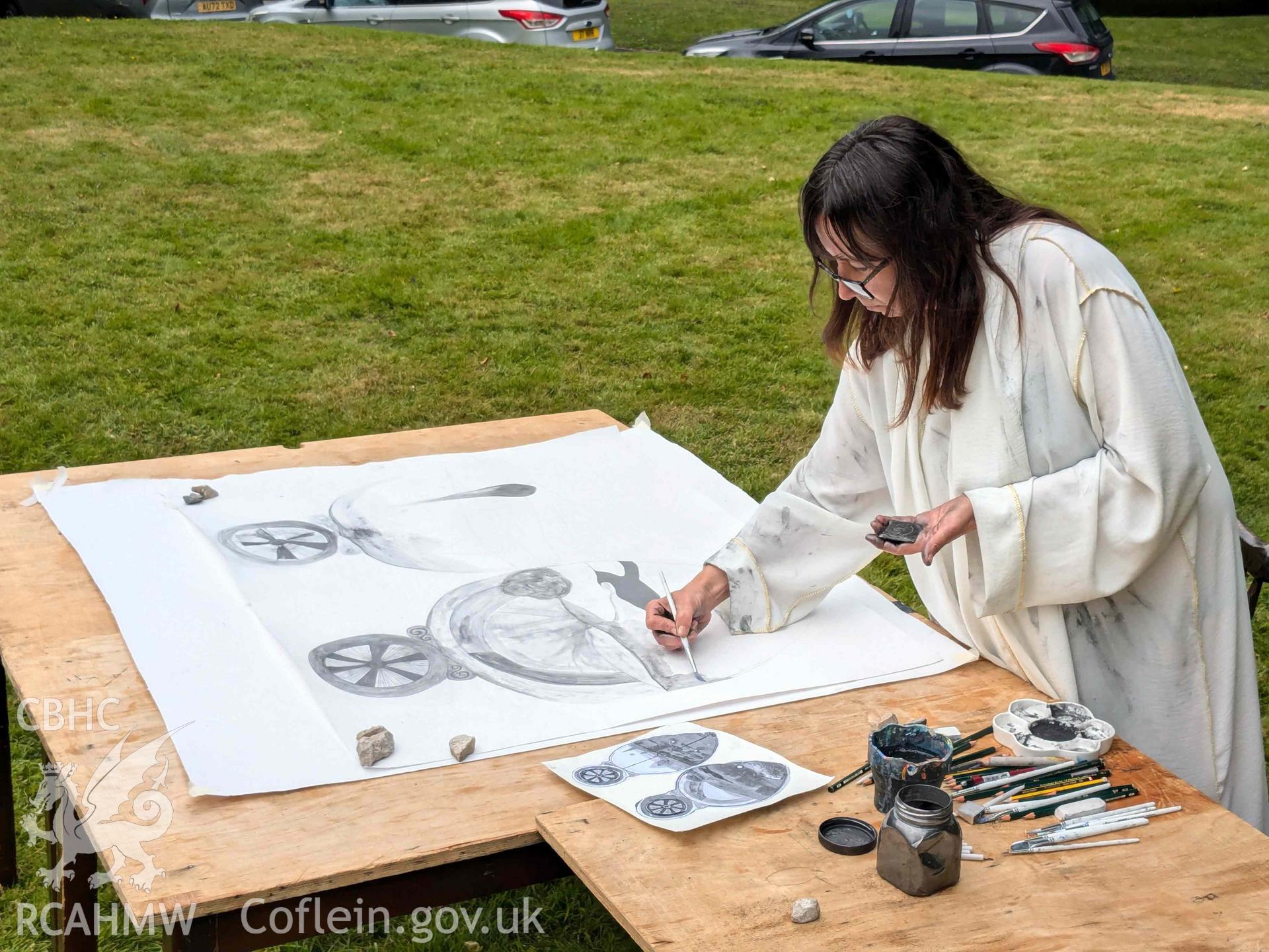 The Ffynogion spoons. Artist Olivia Hicks RA working on a composition based on the spoons at the Ruthin International Arts Festival, June 2024. View showing art performance in grounds of Ruthin Castle