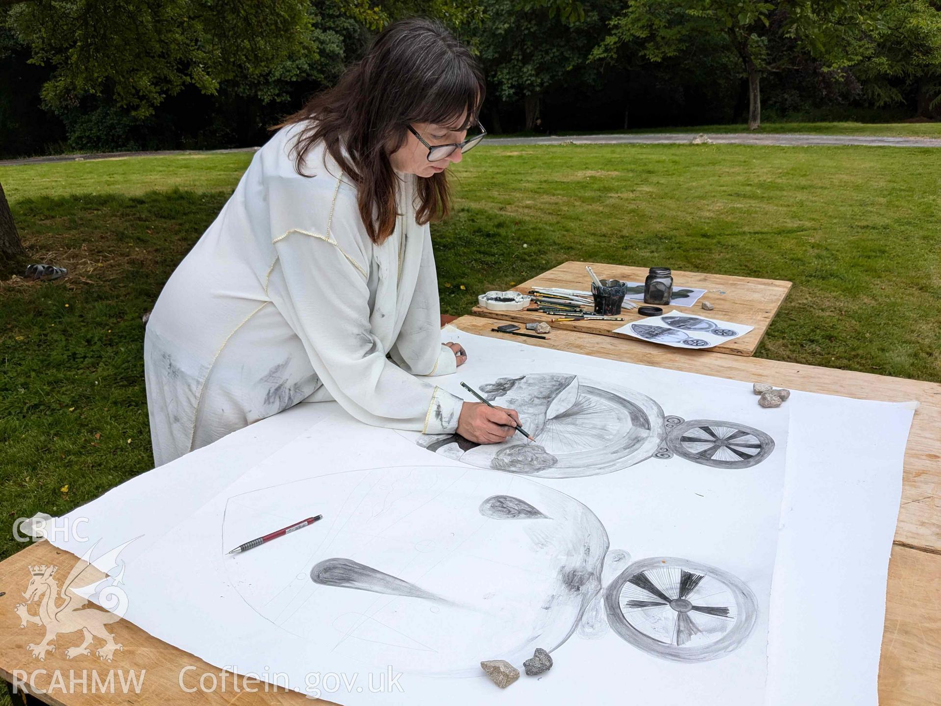 The Ffynogion spoons. Artist Olivia Hicks RA working on a composition based on the spoons at the Ruthin International Arts Festival, June 2024. View showing art performance in grounds of Ruthin Castle