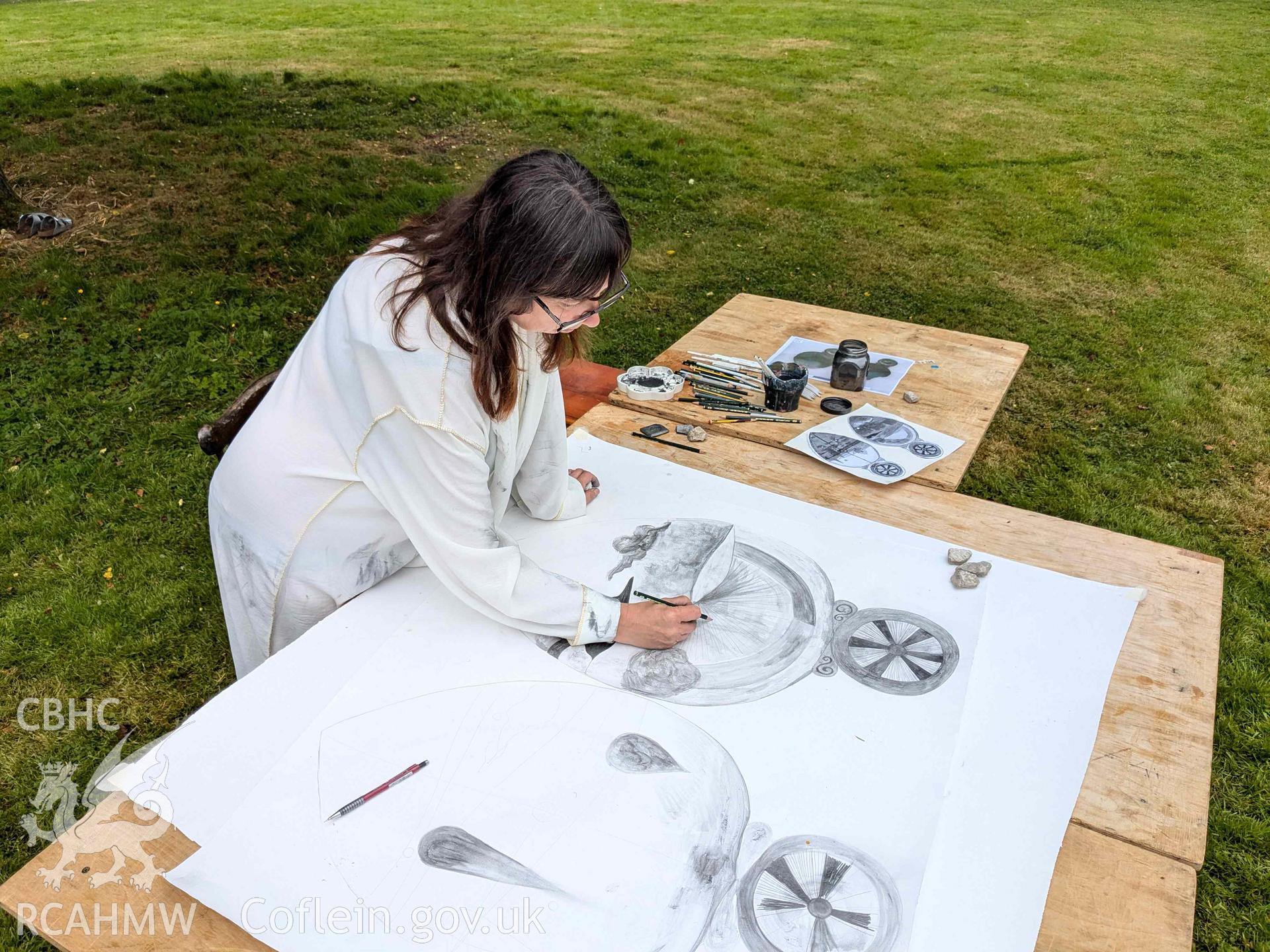 The Ffynogion spoons. Artist Olivia Hicks RA working on a composition based on the spoons at the Ruthin International Arts Festival, June 2024. View showing art performance in grounds of Ruthin Castle