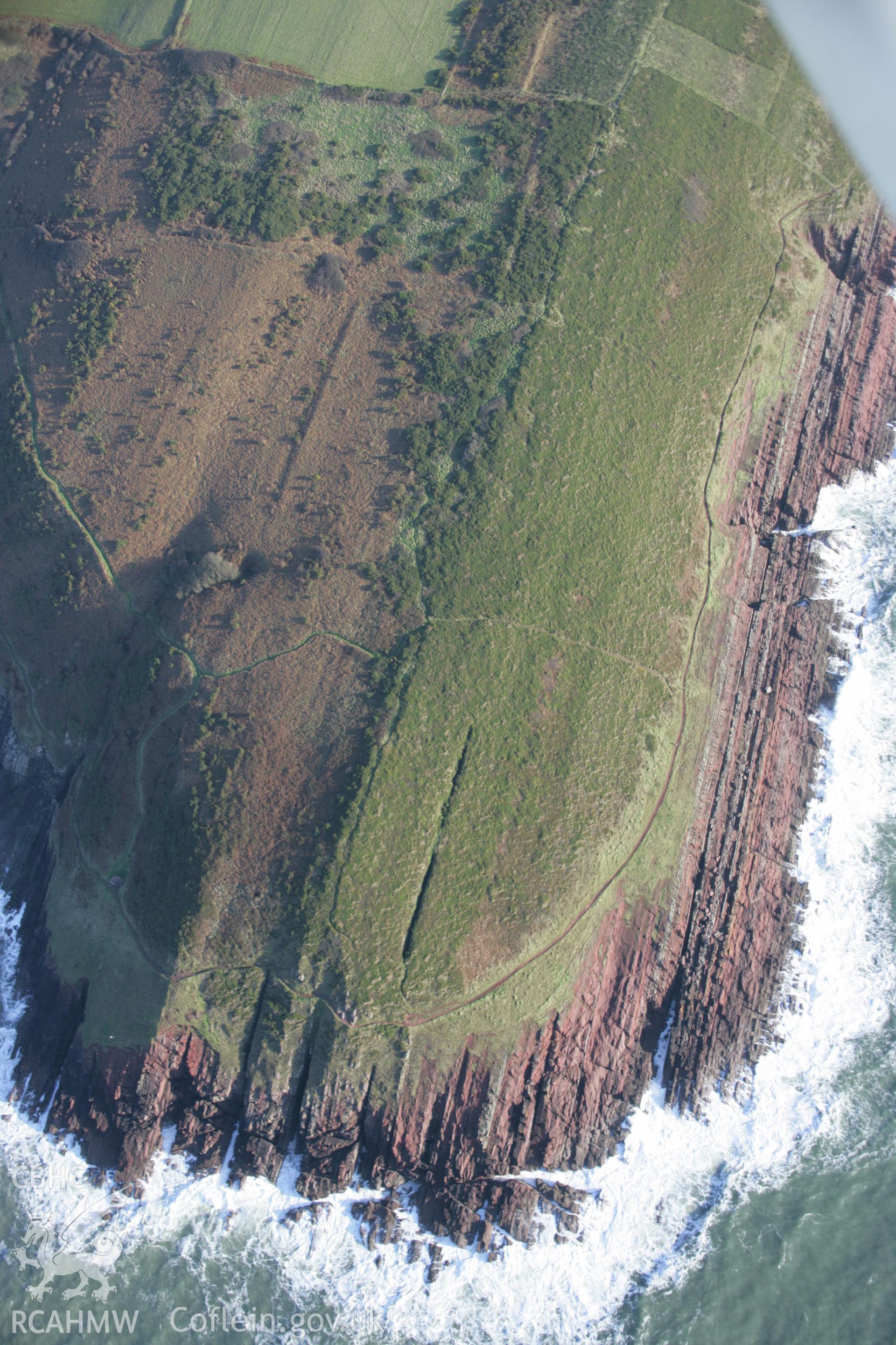 RCAHMW colour oblique aerial photograph of King's Quoit Burial Chamber, with Old Red Sandstone cliffs, viewed looking east. Taken on 11 January 2006 by Toby Driver.