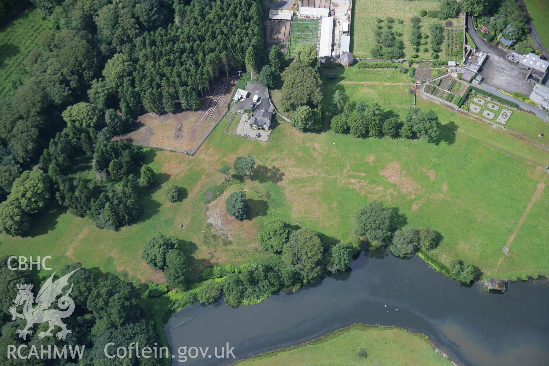 RCAHMW colour oblique aerial photograph of Rug Castle Mound and Prehistoric Funerary Monument with parchmarks showing. Taken on 31 July 2006 by Toby Driver.