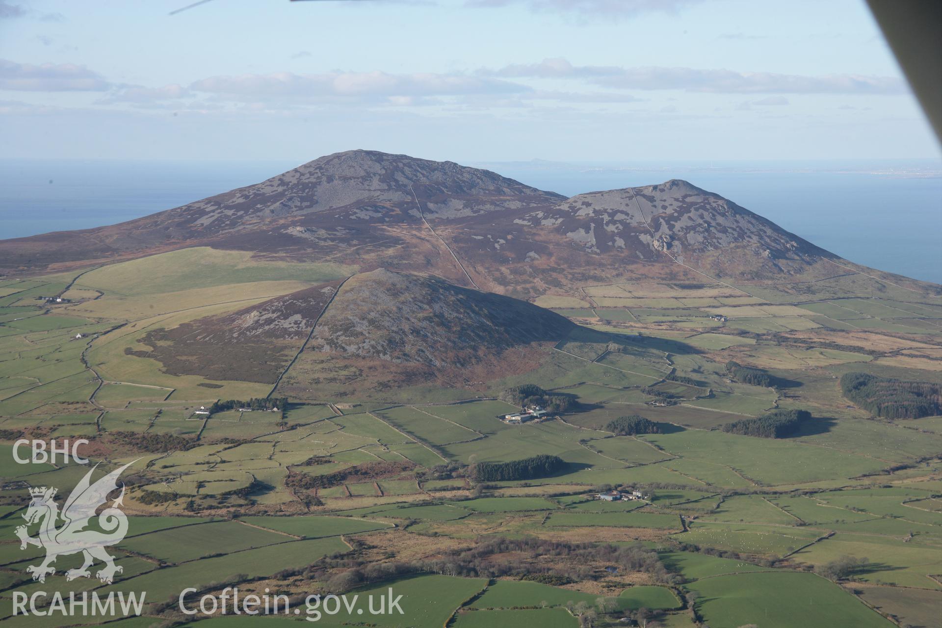 RCAHMW colour oblique aerial photograph of Carnguwch Cairn from the south-east with Yr Eifl beyond. Taken on 09 February 2006 by Toby Driver.