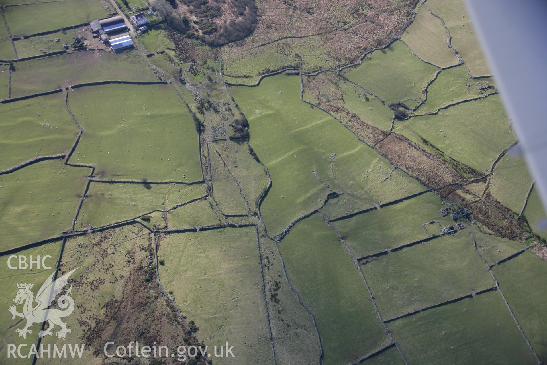 RCAHMW colour oblique aerial photograph of earthworks probably representing a farm yard, a hut group and field system. Viewed from the north-east. Taken on 09 February 2006 by Toby Driver.