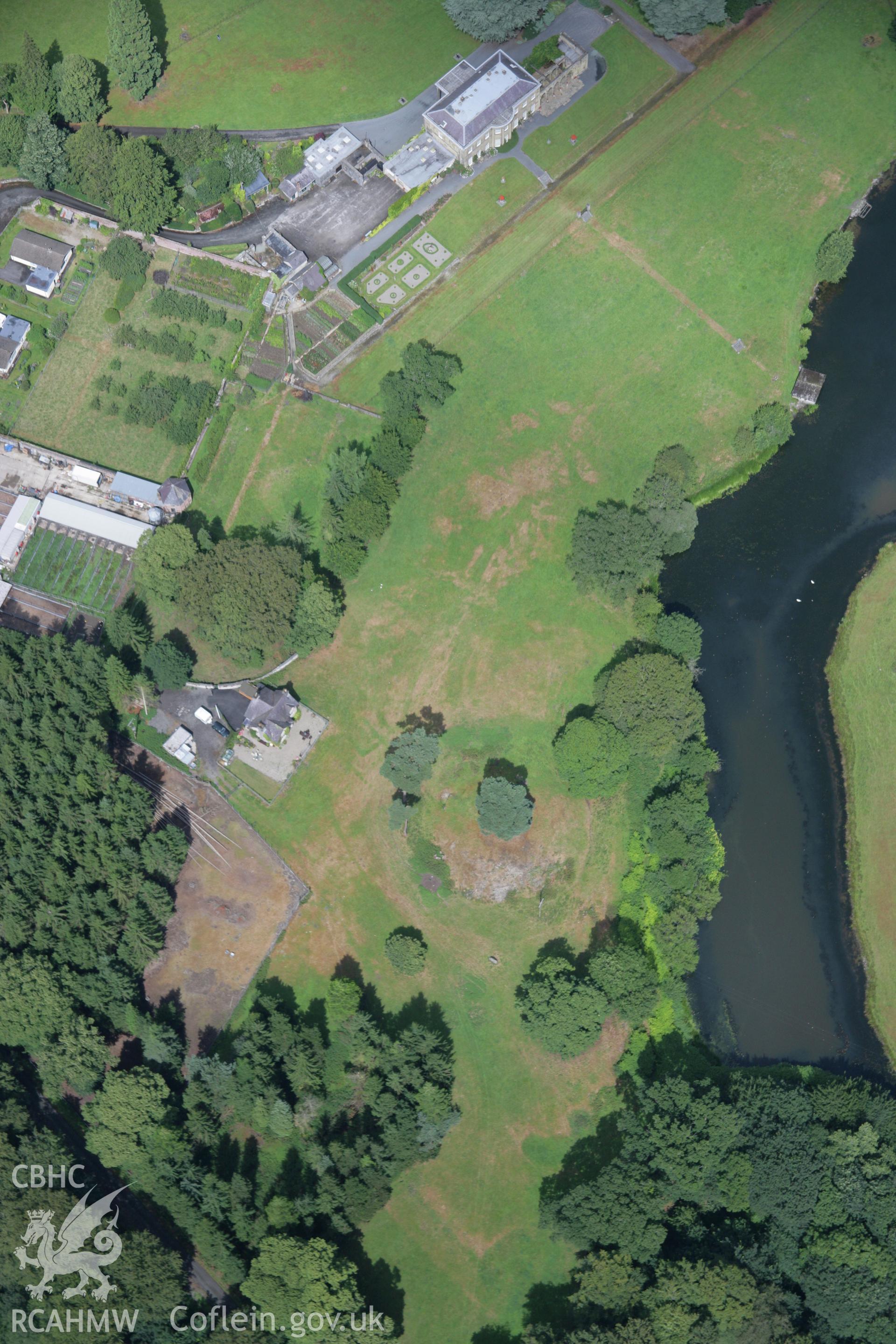 RCAHMW colour oblique aerial photograph of Rug Castle Mound and Prehistoric Funerary Monument with parchmarks showing. Taken on 31 July 2006 by Toby Driver.