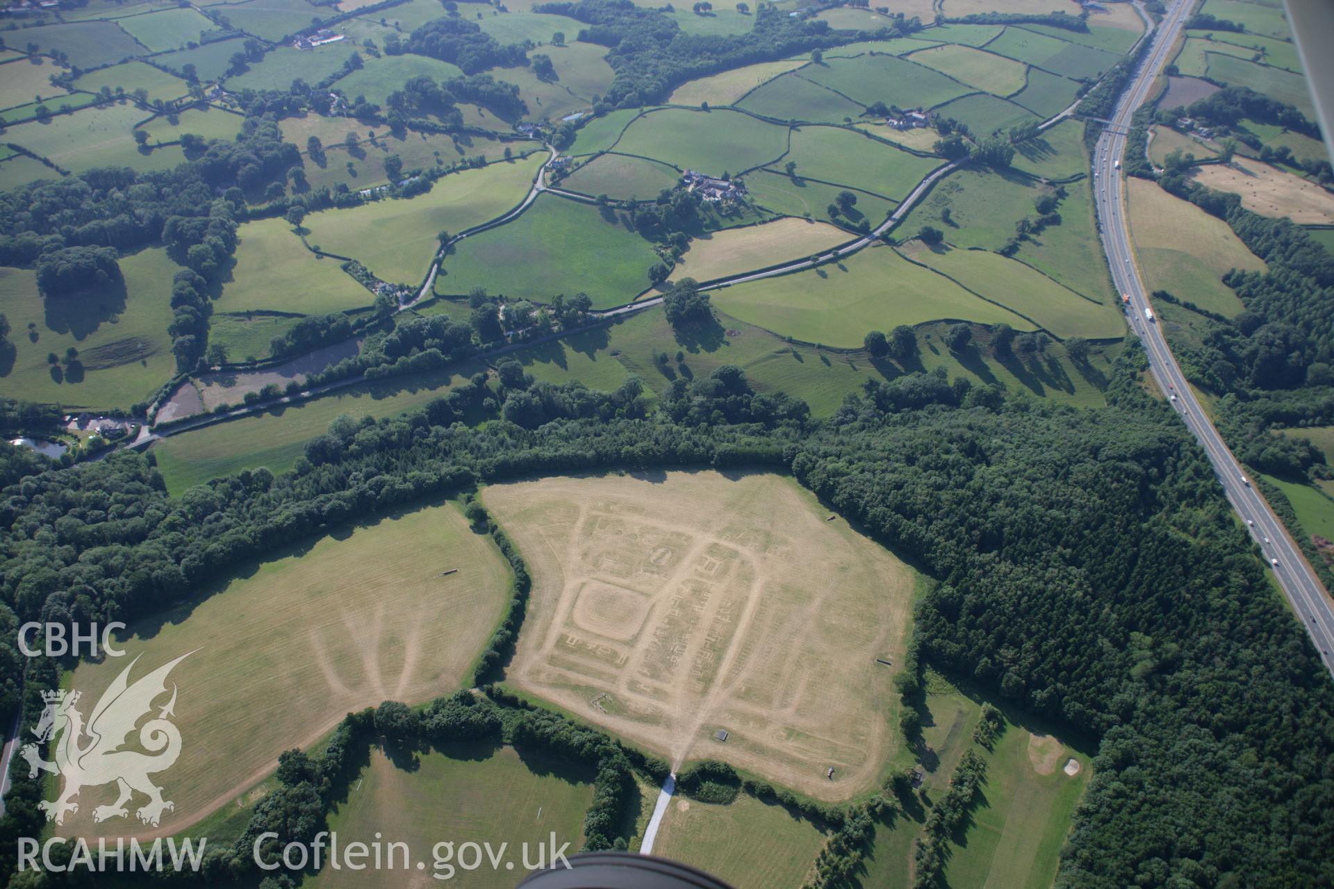 RCAHMW colour oblique aerial photograph of a section of Wat's Dyke from Coed Llys to the Chester to Holywell road. The site of a fair is also visible. Taken on 17 July 2006 by Toby Driver.