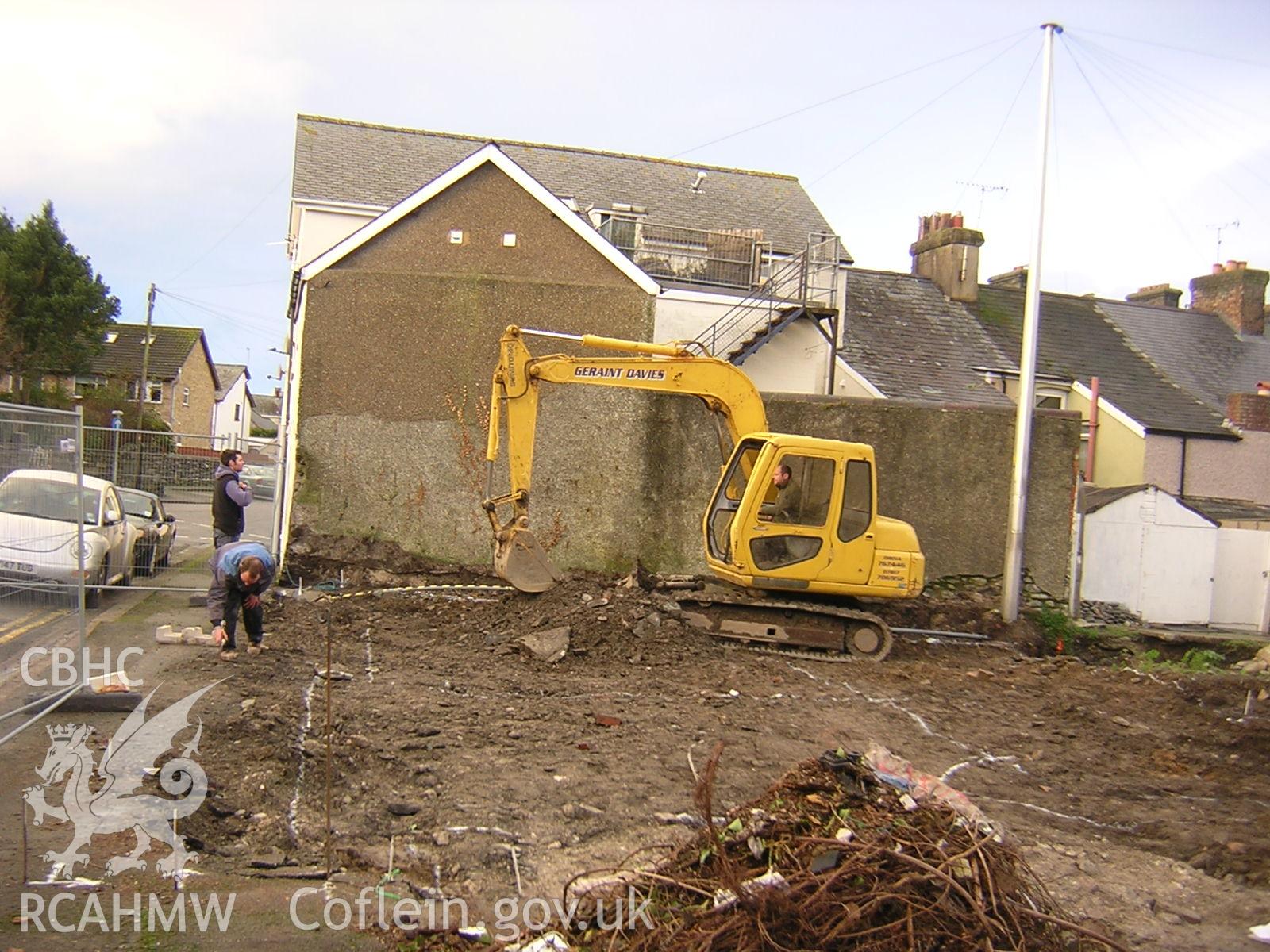 Plate 1: photograph showing view west along street frontage during cutting of foundations; part of Desk Based Research & Watching Brief for Red Lion Street, Tywyn Gwynedd', report no. 1128. Produced by Archaeology Wales in 2012.