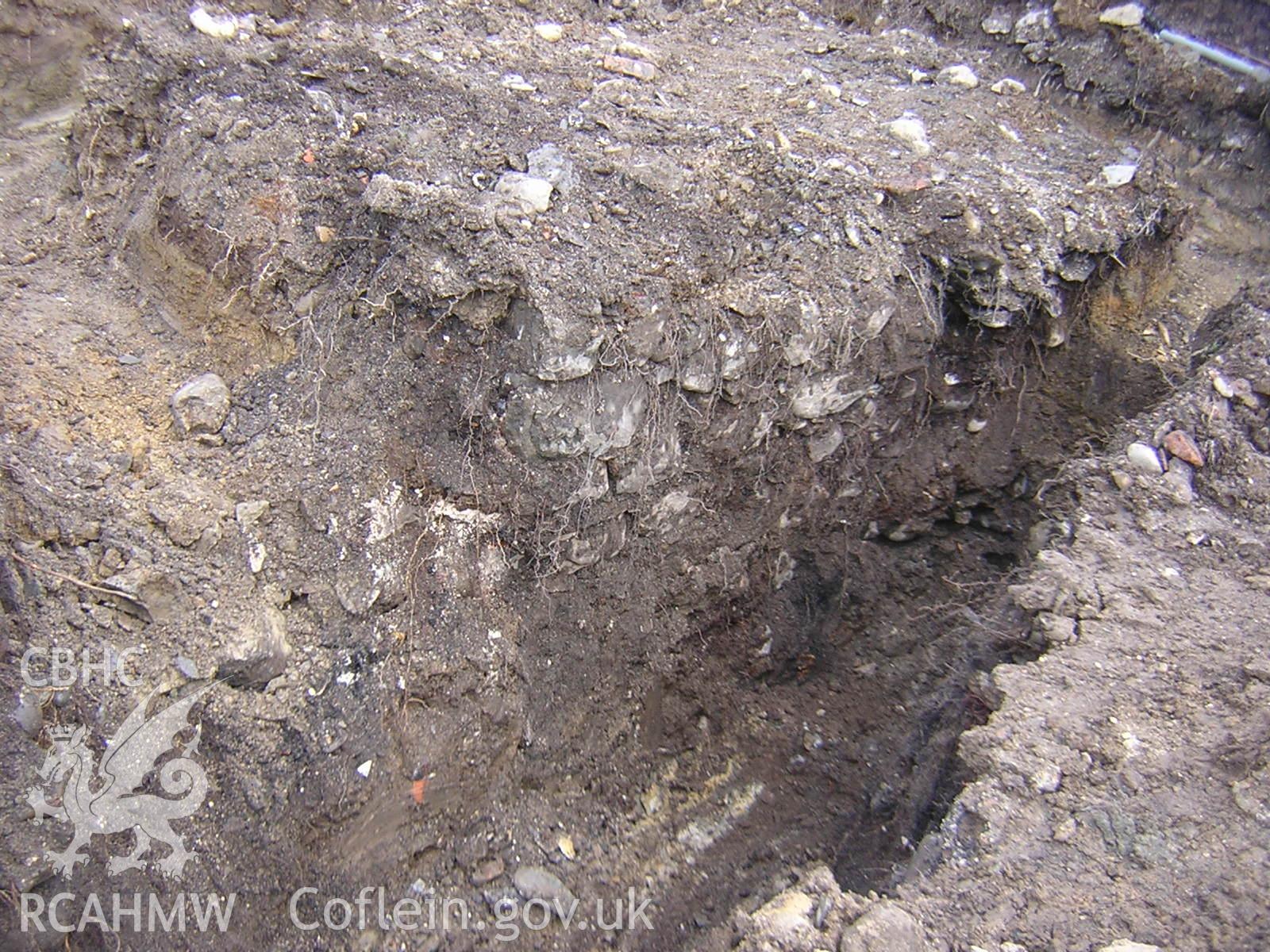 Plate 5: photograph showing View of wall and backfilled cellar in middle of plot; part of Desk Based Research & Watching Brief for Red Lion Street, Tywyn Gwynedd', report no. 1128. Produced by Archaeology Wales in 2012.