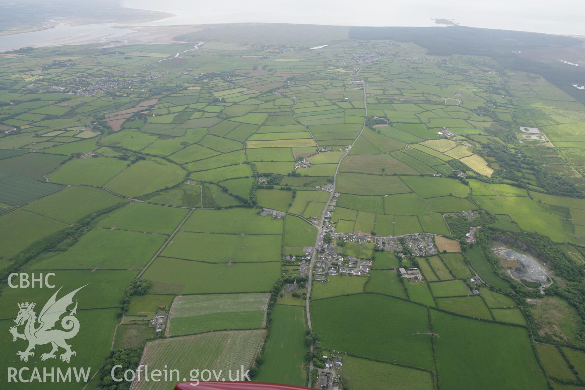 RCAHMW colour oblique photograph of Llangaffo village, with St Caffo's Church, looking south-west towards Caernarfon Bay. Taken by Toby Driver on 13/06/2008.