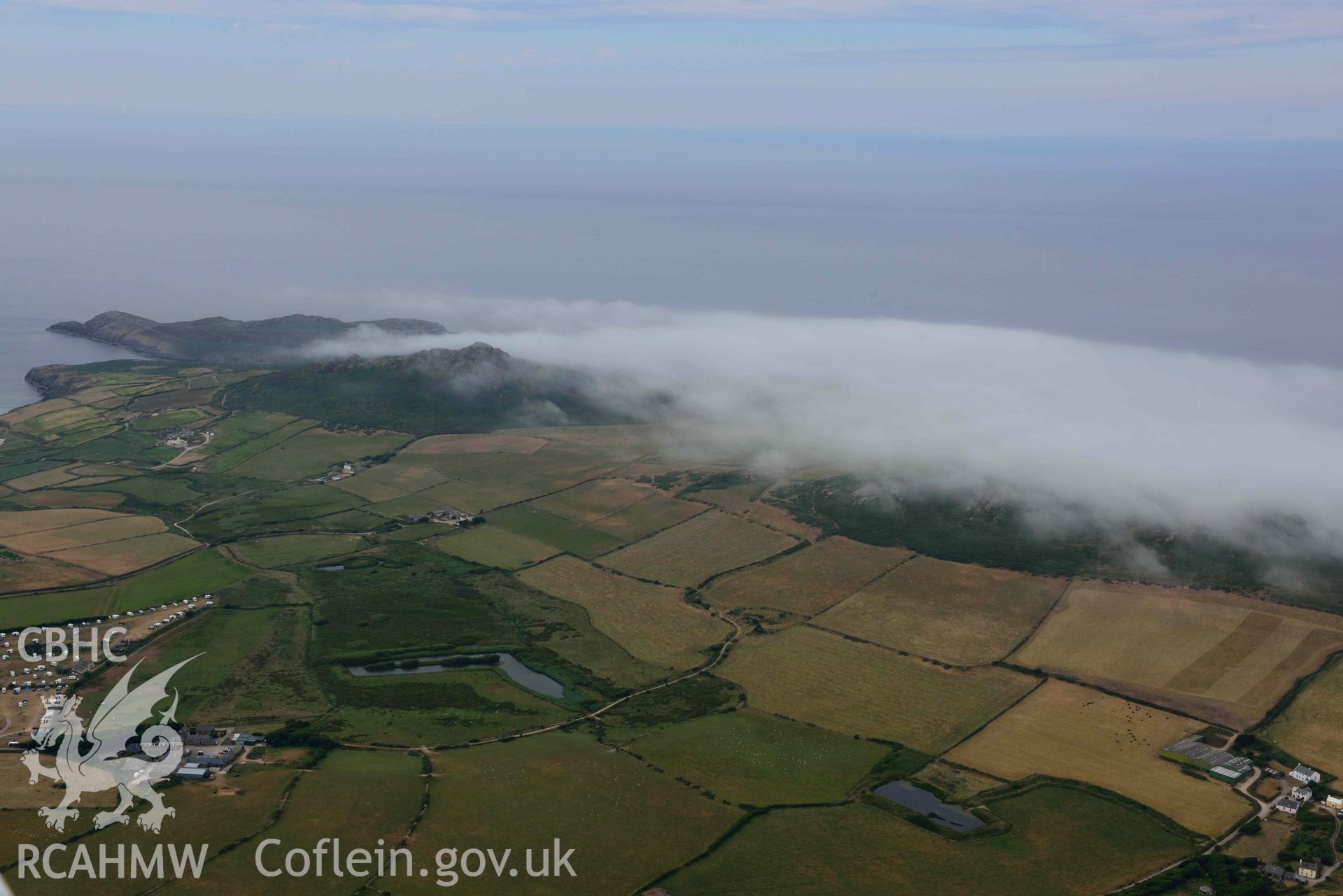 RCAHMW colour oblique aerial photograph of St David's head camp, and Carn Llidi under cloud taken on 11 July 2018 by Toby Driver