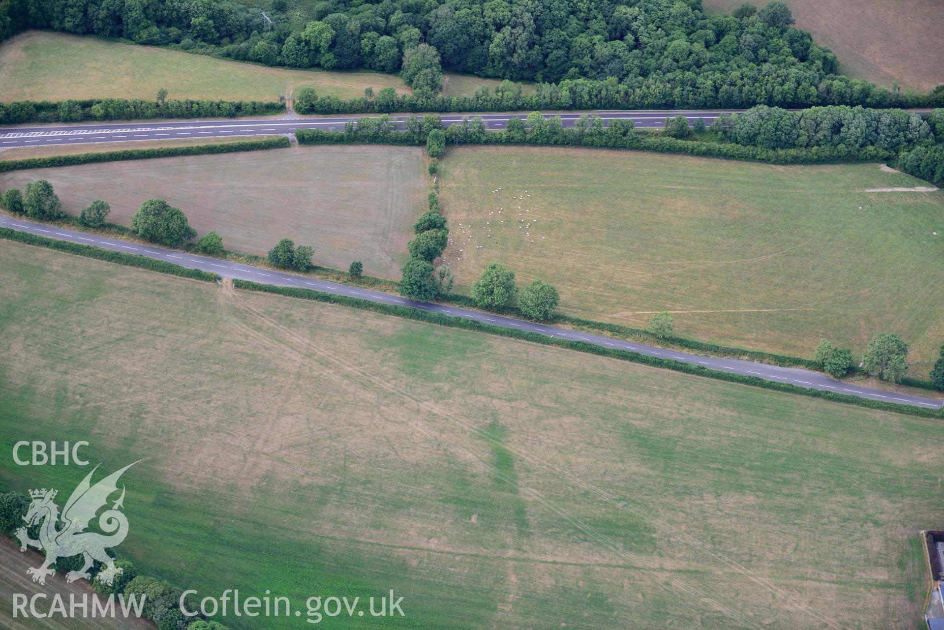 RCAHMW black and white oblique aerial photograph of Round barrow cropmark at Moor; with colour bands rebalanced taken on 17 July 2018 by Toby Driver (NGR: SN230169)