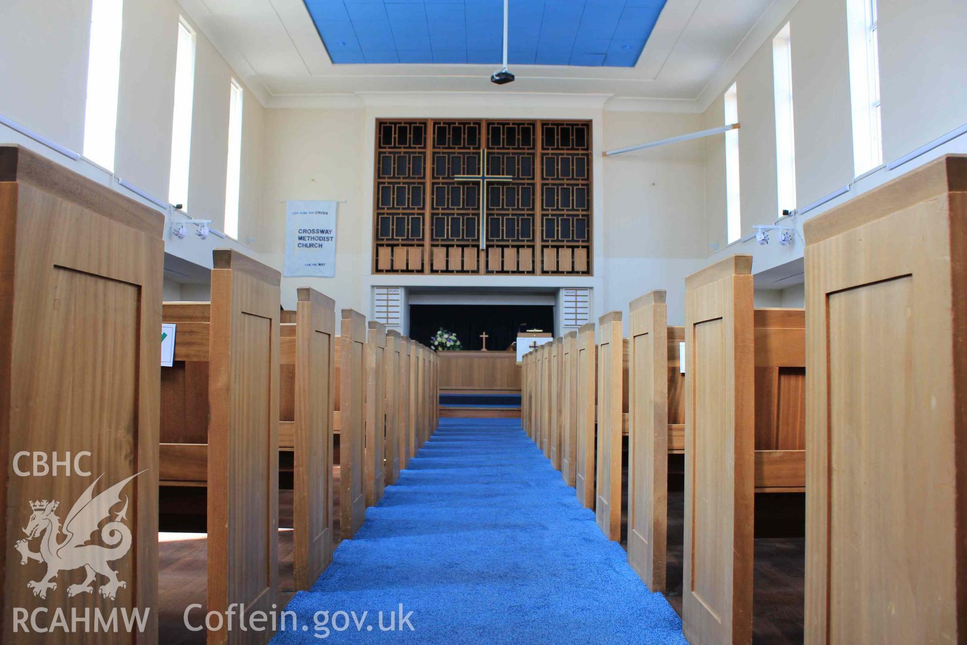 Central aisle towards front altar. Low angle. Pews either side