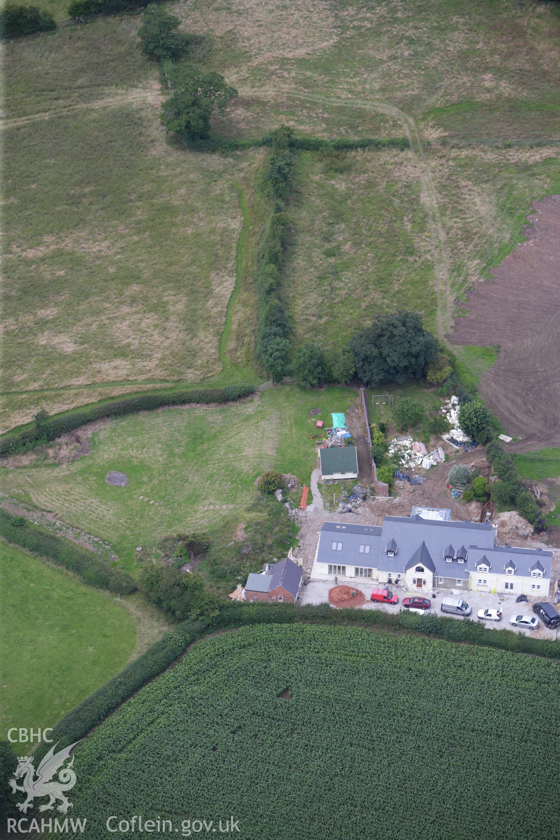 RCAHMW colour oblique aerial photograph of a section of Offa's Dyke, or Whitford Dyke, northwest and southeast of Brynbella Mound. Building work is visible nearby. Taken on 30 July 2009 by Toby Driver