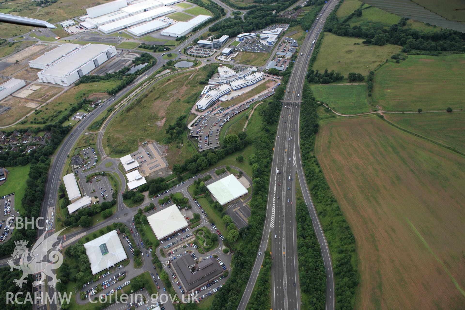 RCAHMW colour oblique aerial photograph of Gwern-y-Cleppa Long Barrow and the industrial estate near Tredegar House. Taken on 09 July 2009 by Toby Driver