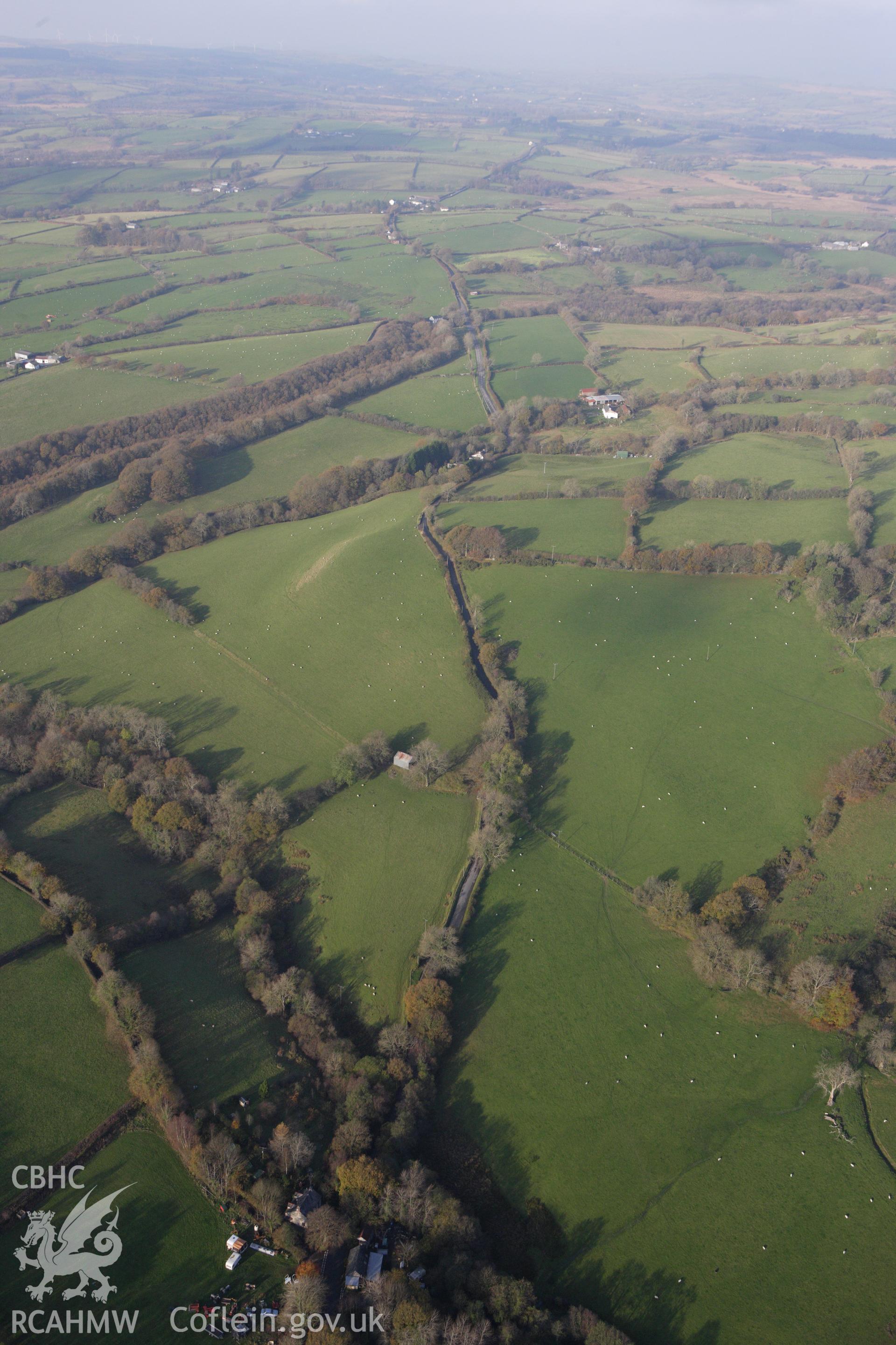 RCAHMW colour oblique aerial photograph of Tre-Coll Hillfort with Sarn Helen passing to the south-east. Taken on 09 November 2009 by Toby Driver